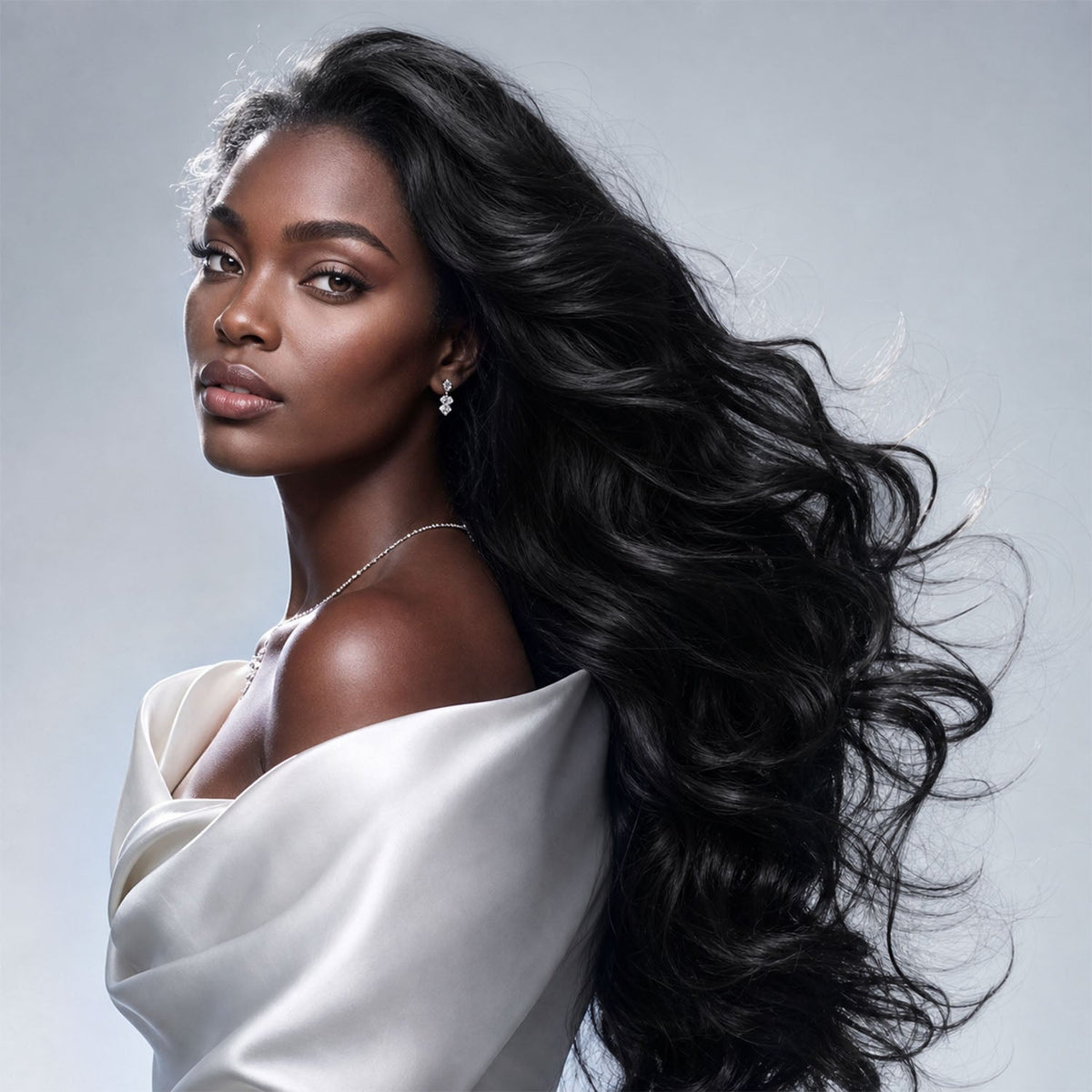 Portrait of a woman with long dark waves against a pale gray background