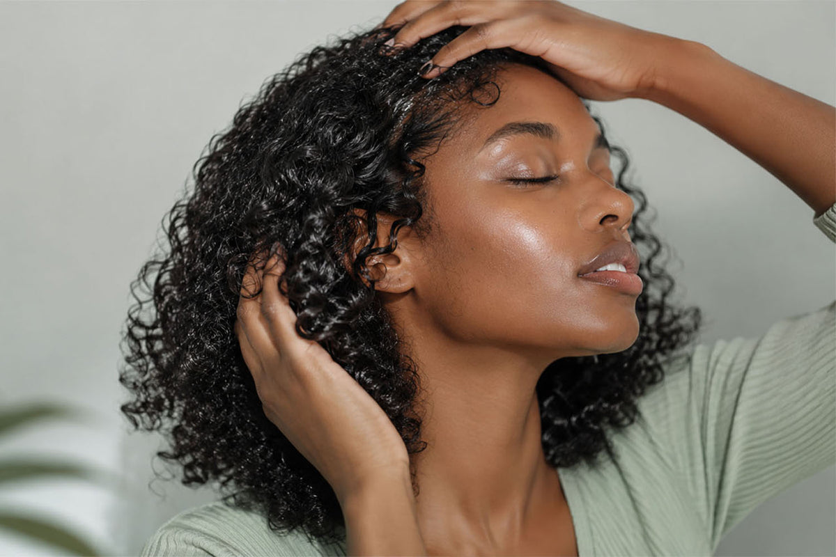 Woman gently arranging dark curls around the hairline